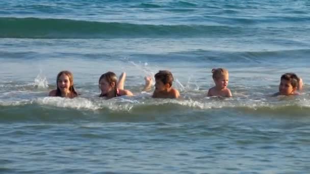 Los niños yacen en las olas de la orilla del mar — Vídeos de Stock