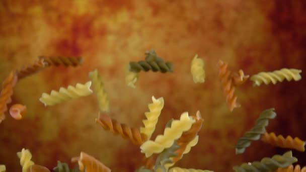 Gekleurde pasta fusili stuiteren op een gele achtergrond — Stockvideo