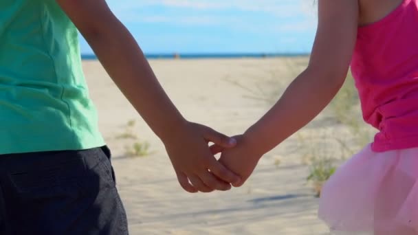 Закрытие детей, держащихся за руки на пляже — стоковое видео