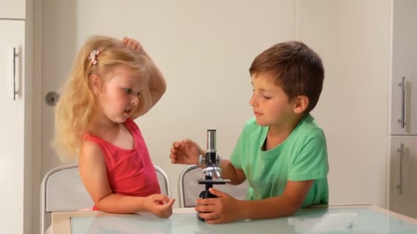 Boy shows a girl how to look through a microscope — Stock Video