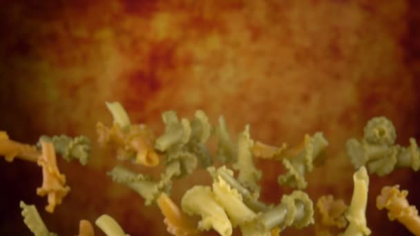 Pasta de colores campanelle volar sobre fondo amarillo — Vídeo de stock