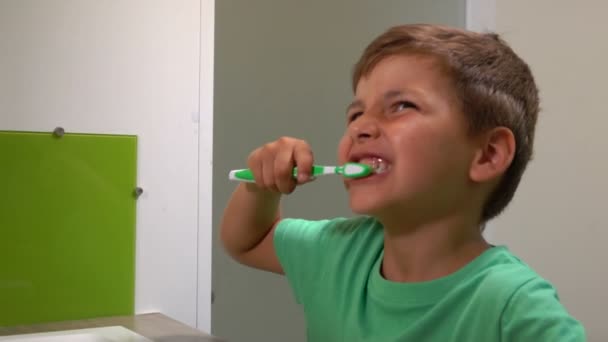 Menino de t-shirt verde limpa os dentes — Vídeo de Stock