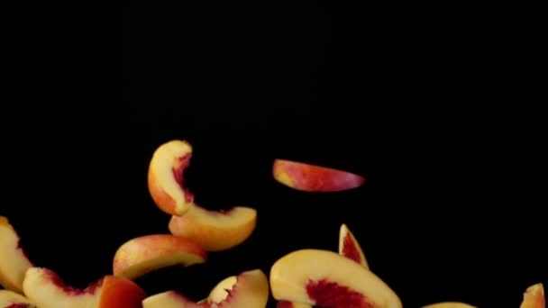 Персикові скибочки літають вгору на чорному тлі — стокове відео