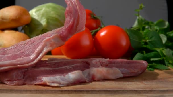Мясо стейк падает на фоне помидоров — стоковое видео