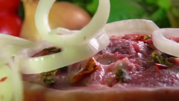 Primer plano de los aros de cebolla que caen sobre la carne cruda — Vídeos de Stock