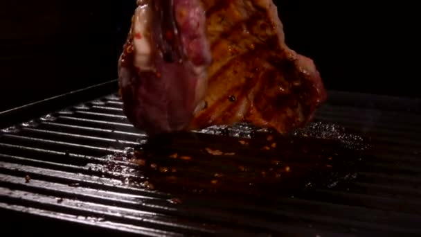 Мясо стейк вращается на гриле с мясными щипцами — стоковое видео