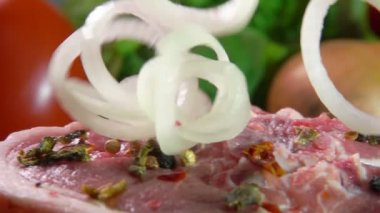 Soğan halkaları çiğ domuz etinin üzerine düşüyor. 