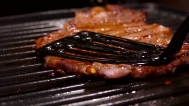 Bistecca di carne viene premuto alla griglia con una spatola — Video Stock