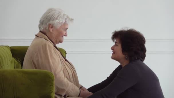 Mulheres bonitas conversando com sua mãe idosa em um quarto branco — Vídeo de Stock