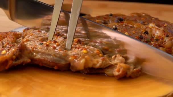 Faca corta um bife de carne preparado em pedaços no tabuleiro — Vídeo de Stock