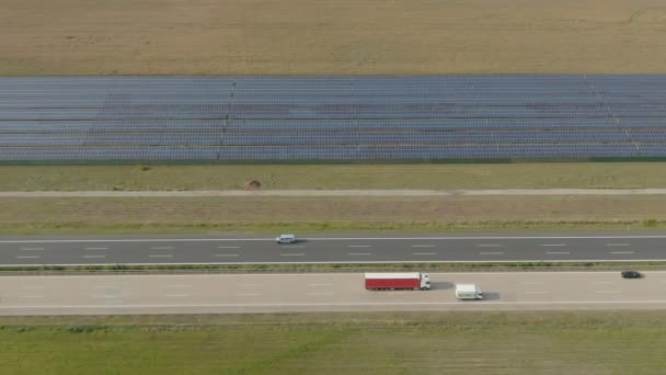 Flygpanorama över ett brett fält med solpaneler bredvid motorvägen — Stockvideo