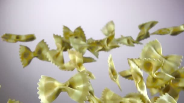 Randig Pasta Farfalle flyga på en vit bakgrund — Stockvideo