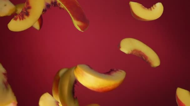 Pfirsichscheiben fliegen diagonal auf dem roten Hintergrund — Stockvideo