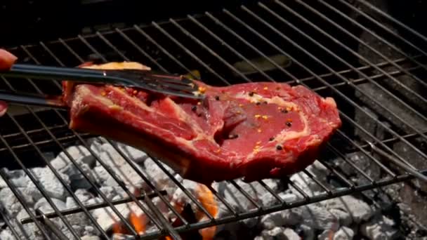 Friptură de carne așezată pe grătar cu clește de carne — Videoclip de stoc
