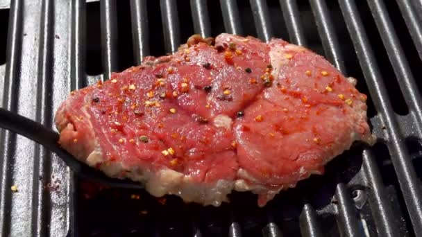 Steak tourné sur le gril avec spatule de cuisine noire — Video