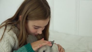 Mutlu güzel kız küçük sevimli bir tavşanı okşuyor.