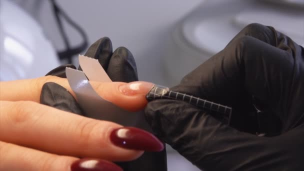 Manicure verwijdert de papieren basis na nagelverlenging — Stockvideo