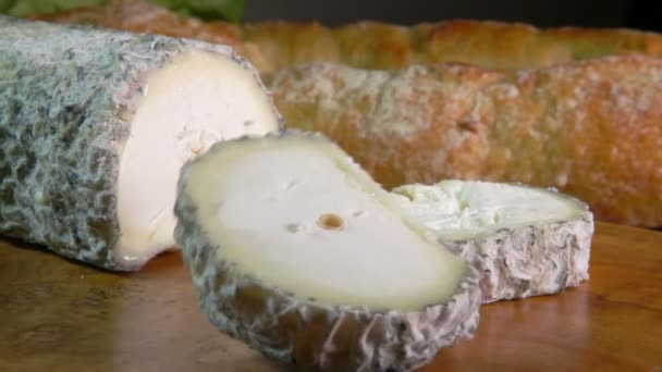 Кусок козий сыр Сен-Мор-де-Турен падает на деревянную доску — стоковое видео