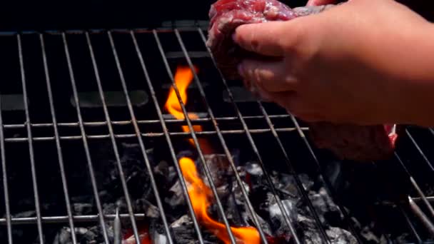 Hand lägger en bit fläskkött biff på grillen — Stockvideo