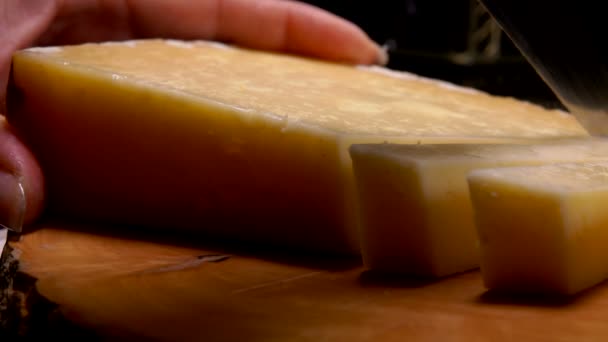 Cuchillo corta un queso parmesano duro en rodajas gruesas — Vídeo de stock