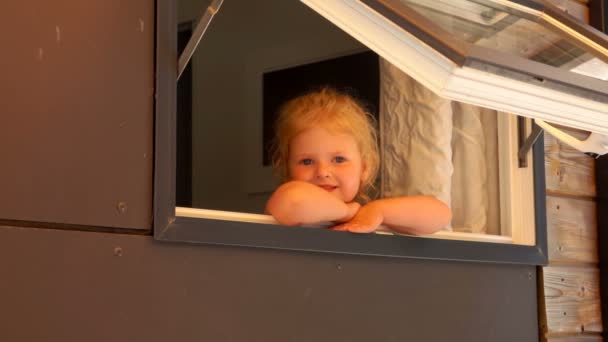 Little girl looks out of the open window — Stock Video