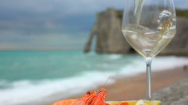 Beyaz şarap arkaplanda karides ve limon olan bir bardağa doldurulur.