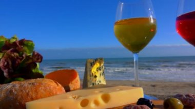 Deniz kenarında romantik bir piknik şarap, çeşitli peynirler ve zeytinlerle