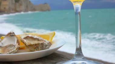 Okyanusun arka planında taze istiridye ve limon olan beyaz tabak.