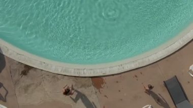 Aerial shooting of three children diving into the round swimming pool