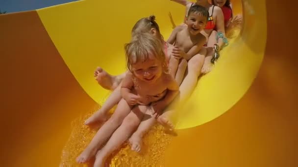 Frau und glückliche Kinder fahren die orangefarbene Rutsche im Wasserpark hinunter — Stockvideo