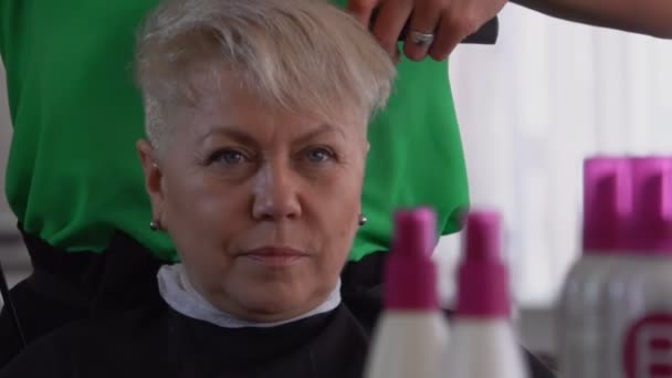 Рукавичка робить коротку зачіску для задоволеної жінки-клієнтки. — стокове відео