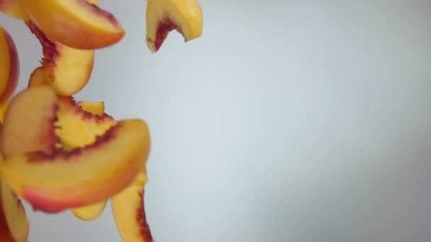 Pfirsichscheiben fliegen diagonal auf dem weißen Hintergrund — Stockvideo