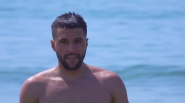 Deniz sörfünün arka planında genç yakışıklı bir adamın portresi. 