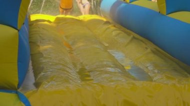 Happy boy is gliding through the slippery yellow blue slide