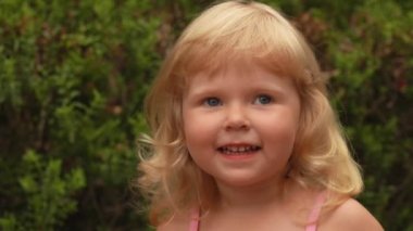 Portrait of a beautiful little blond girl smiling and laughing outdoors