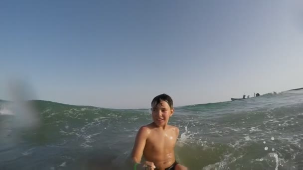 Boy is running backward and falling into the sea wave — ストック動画