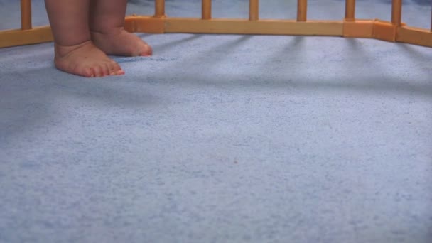 Bonito bebê pés dar os primeiros passos em um cobertor azul no parque infantil — Vídeo de Stock