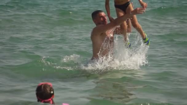 Papá joven ayuda al niño a saltar al agua del mar — Vídeo de stock