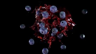 Delicious blueberries are flying up with the splashes of juice in slow motion
