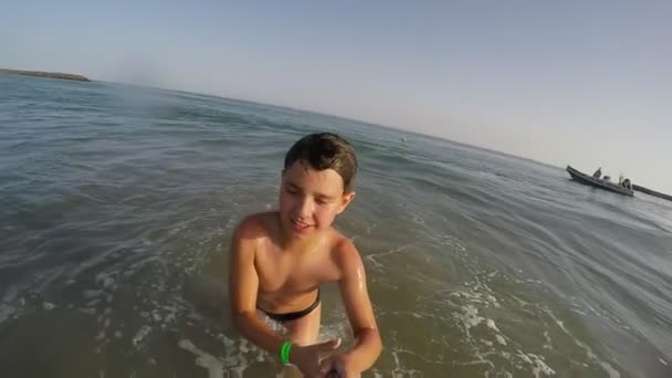 Smiling boy showing big thumb and running through the sea — Stok video