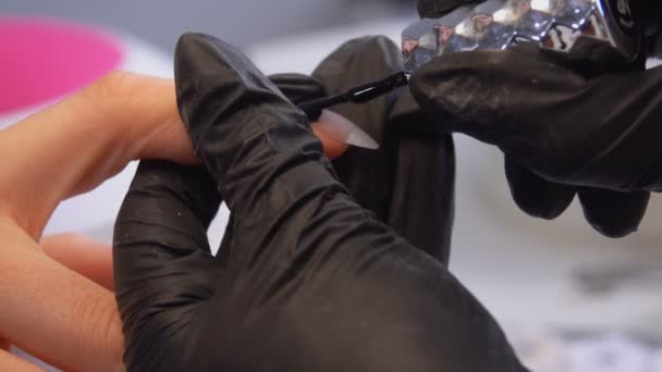 Manicurists hands in black gloves painting manicured nails with a black gel — 비디오