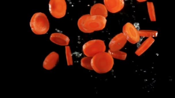 Fresh choped organic carrots flying with dropes of water on a black background — Stok video