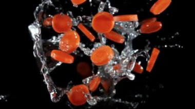 Fresh carrots flying with the splashes of water on a black background