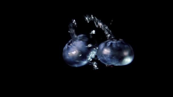 Two large blueberries are flying and colliding on a black background — 图库视频影像