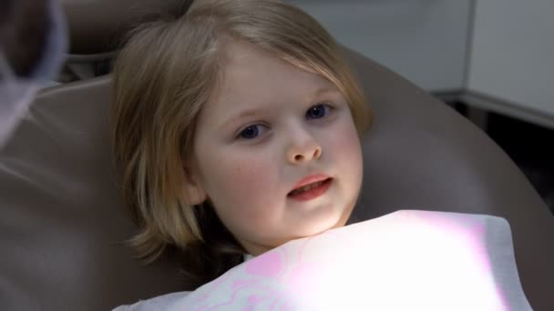 La bambina è seduta su una sedia speciale e sorride al suo dentista — Video Stock