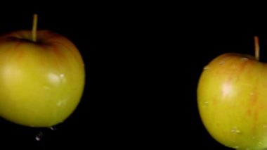 Siyah arka planda iki elma birbirine doğru uçuyor.