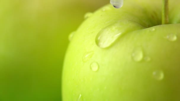 Super gros plan d'une pomme verte avec une goutte d'eau coulant sur la surface — Video