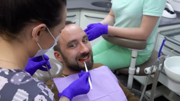 Чоловічий пацієнт жує спеціальний стоматологічний індикатор, і стоматолог оглядає його — стокове відео