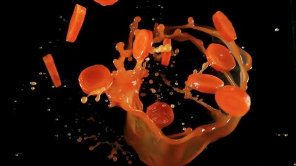 Carottes fraîches hachées volent avec des éclaboussures de jus sur un fond noir — Video