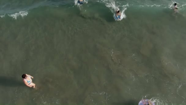 Aerial shooting of children swimming on the inflatable donuts on the waves — Stok video